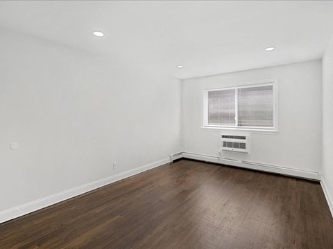 A room with wooden flooring and a window with blinds.