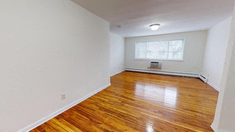 an empty living room with wood floors and a window