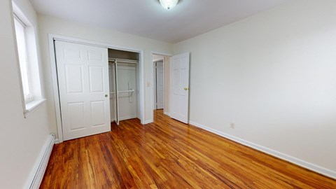 a bedroom with wood floors and white closets