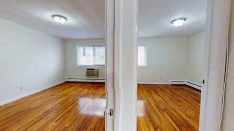 an empty living room with wood floors and white walls