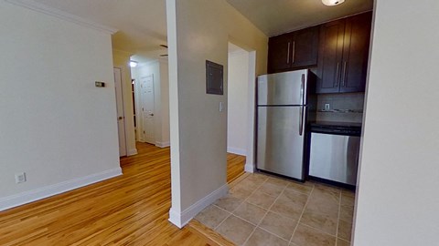 a kitchen and a living room with a stainless steel refrigerator