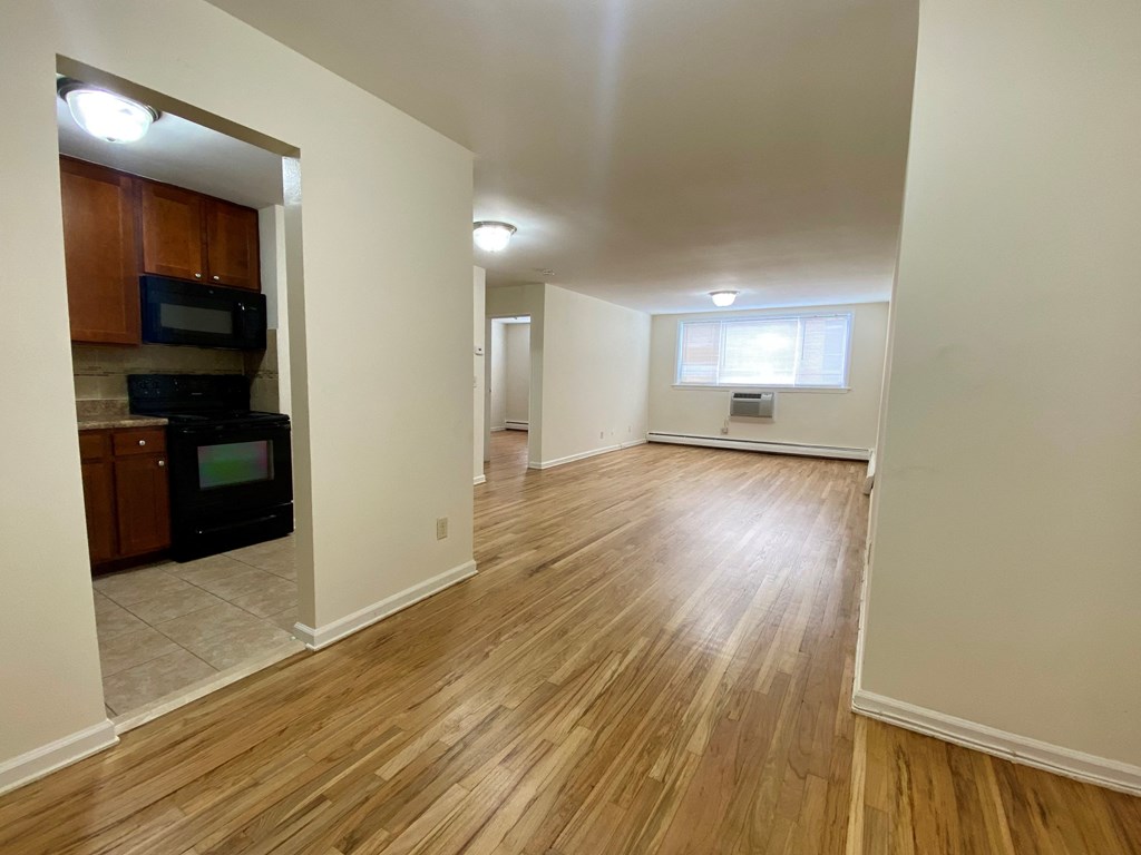 an empty living room and kitchen with wood flooring and a window