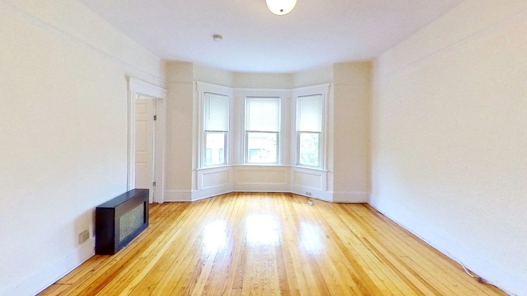 an empty living room with white walls and wood floors