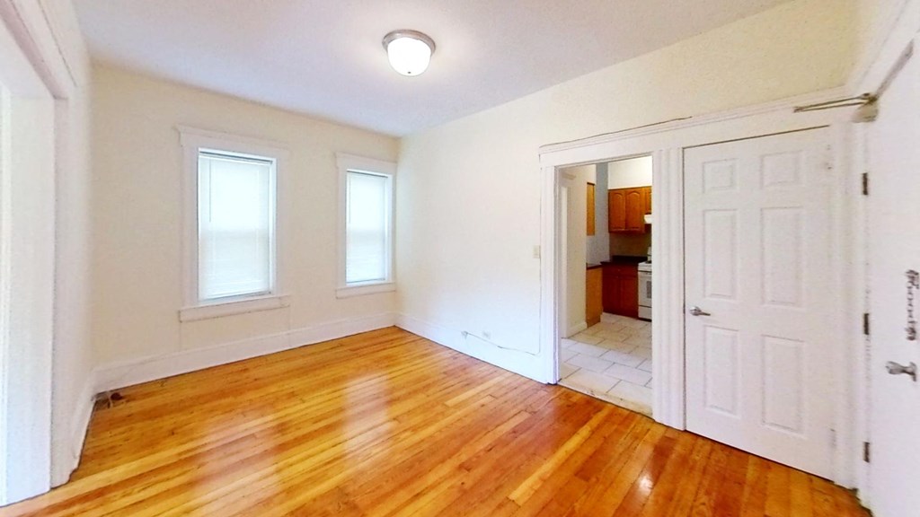 an empty living room with a wooden floor and white doors