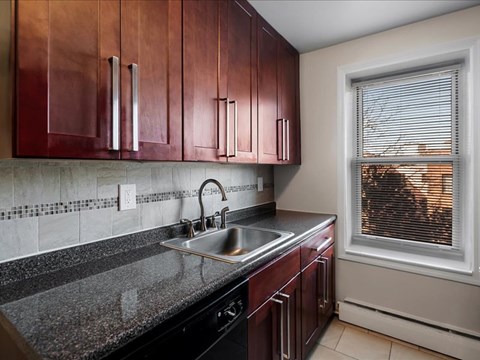 A kitchen with brown cabinets and a black dishwasher.