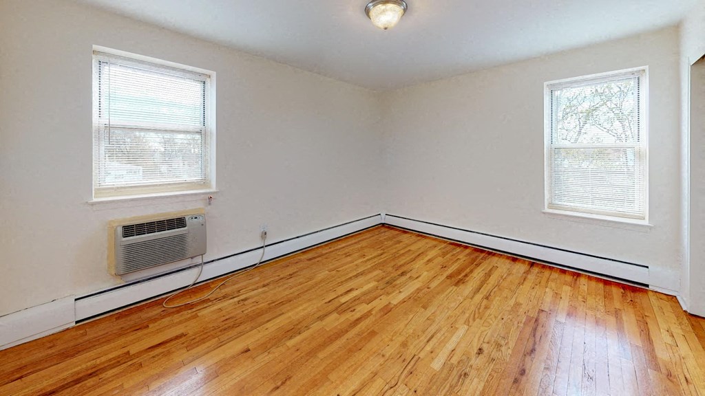 an empty living room with wood floors and a radiator