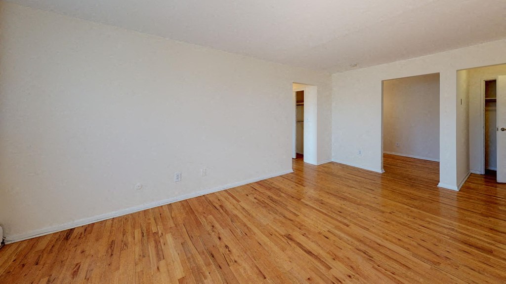 an empty living room with wood floors and white walls