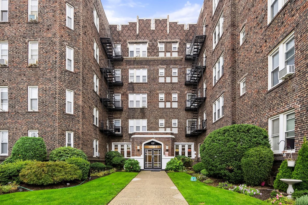 the exterior of a brick apartment building with a courtyard and grass