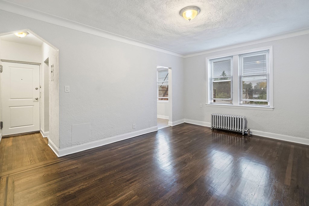 an empty living room with hardwood flooring and a window