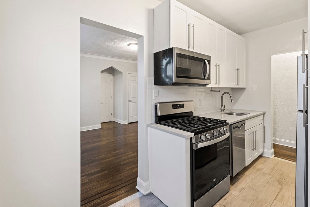 an empty kitchen with white cabinets and a stove and microwave
