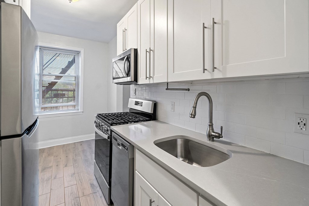 an empty kitchen with white cabinets and a sink