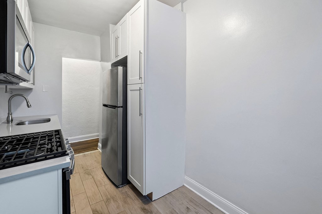 a renovated kitchen with white cabinets and a stainless steel refrigerator