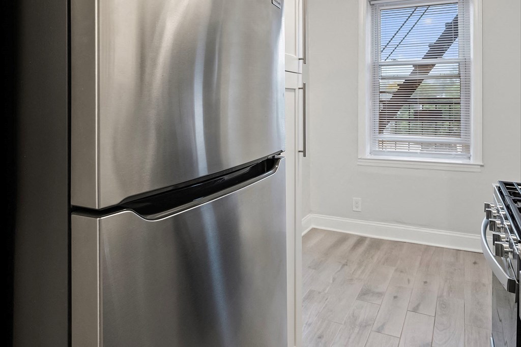 a stainless steel refrigerator in a kitchen next to a window