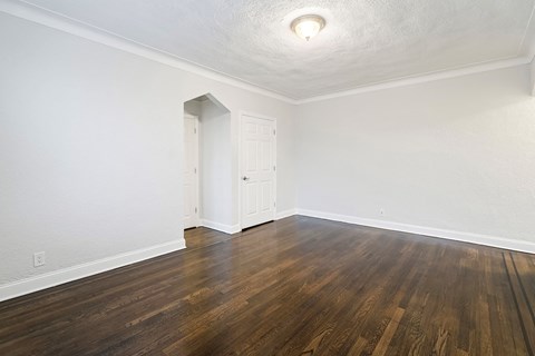 an empty living room with wood flooring and white walls