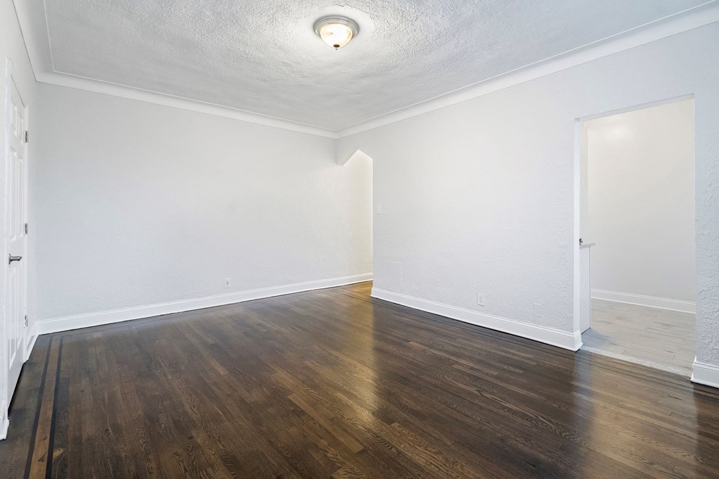 an empty living room with white walls and wood flooring