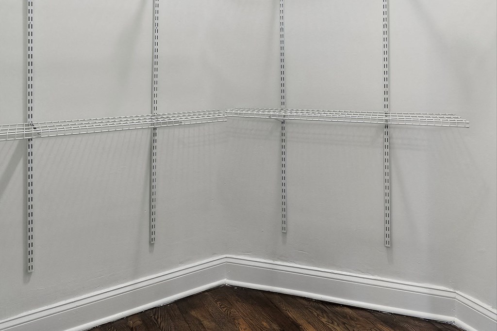 the corner of a room with white walls and a wooden floor