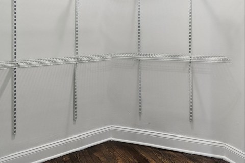 the corner of a room with white walls and a wooden floor