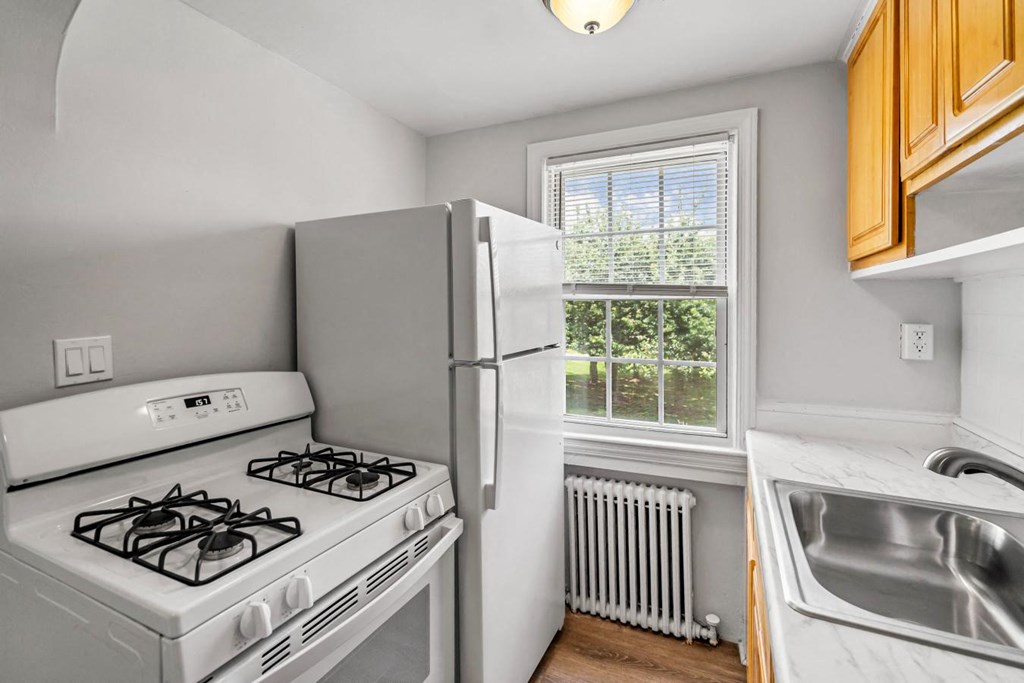 a kitchen with a stove and a refrigerator next to a window