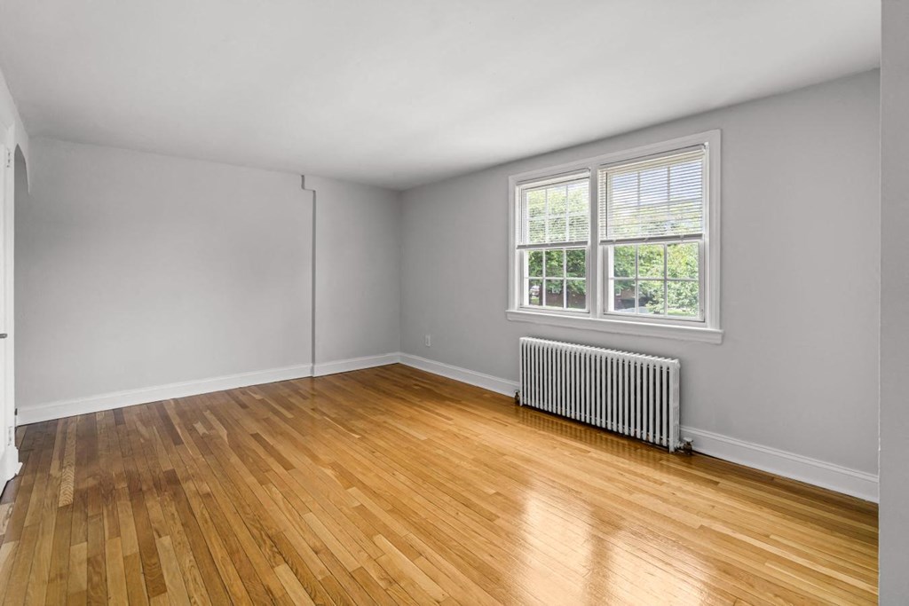 an empty living room with wood floors and a window