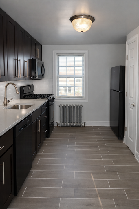 A kitchen with black cabinets and a white door.