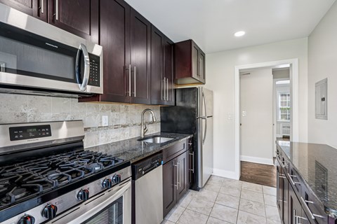 A kitchen with dark brown cabinets and a black stove top oven.
