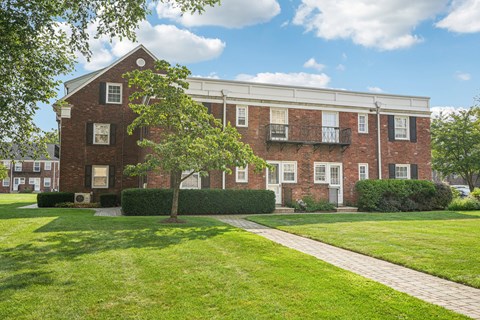 A red brick building with white trim and a balcony.