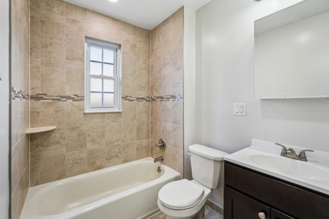 A bathroom with a tub, toilet, and sink.