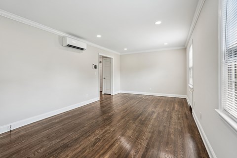 A room with wooden flooring and a window on the right side.