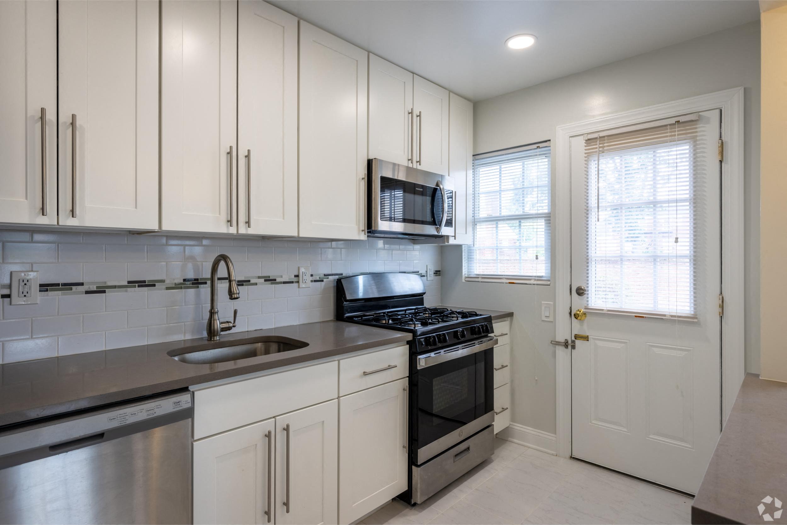 a kitchen with white cabinets and stainless steel appliances and a sink