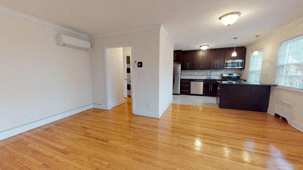 an empty living room and kitchen with wood floors