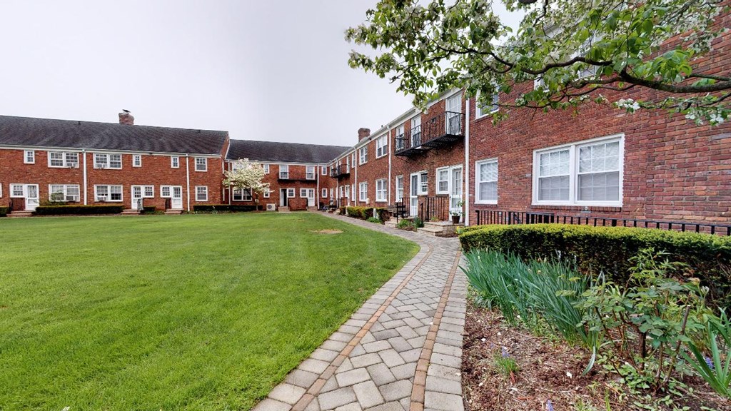 a row of brick houses with a green lawn and a brick sidewalk
