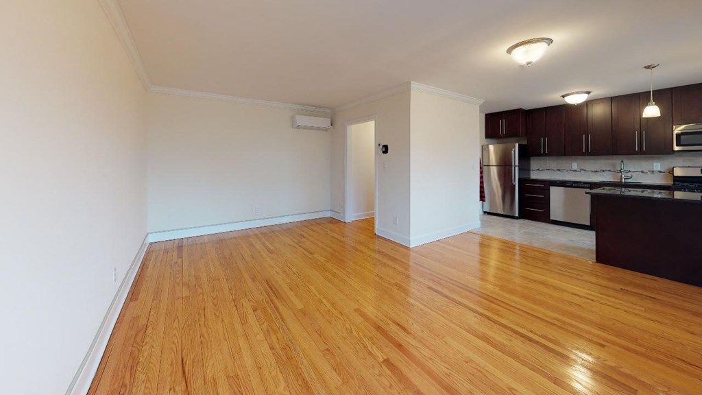 an empty living room and kitchen with wood floors