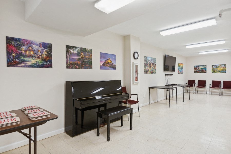 a room with a piano and tables with chairs and paintings on the wall