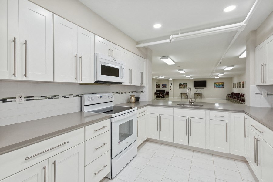 a large white kitchen with white cabinets and stainless steel appliances