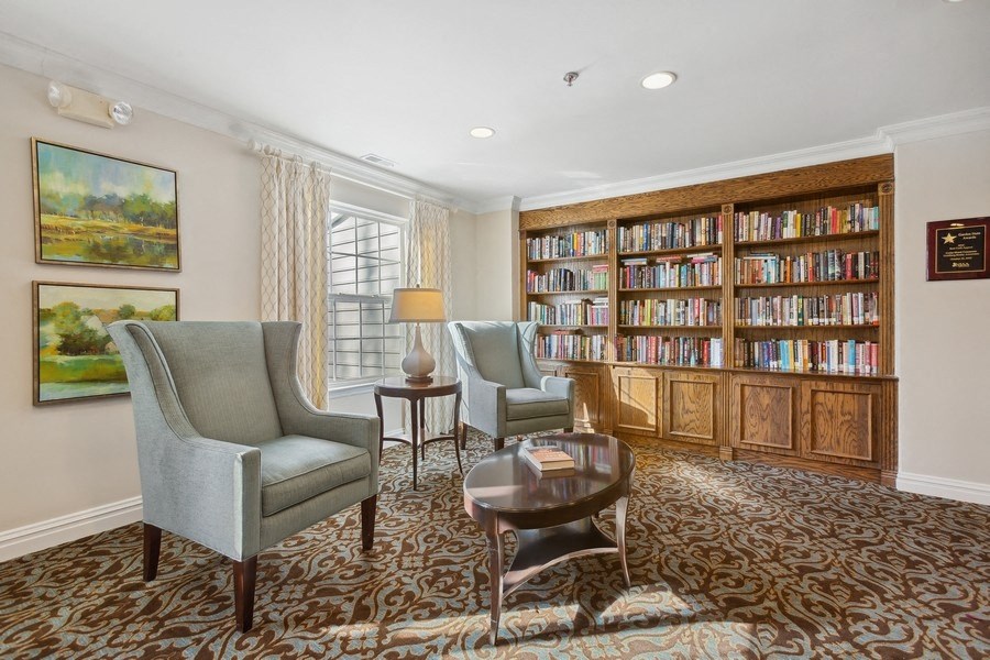 a library with chairs and a table and a book shelf