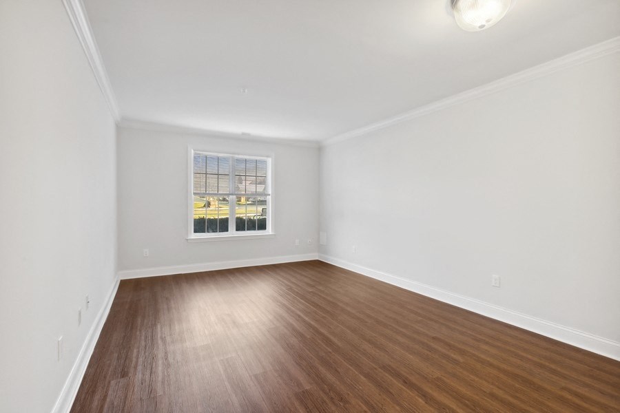 an empty living room with wood floors and a window