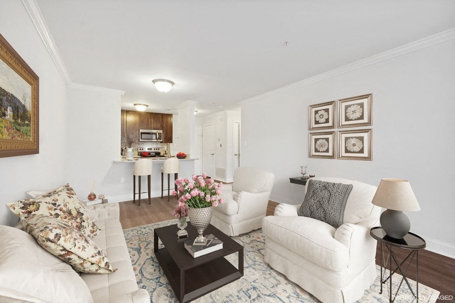 a living room with white furniture and a kitchen in the background