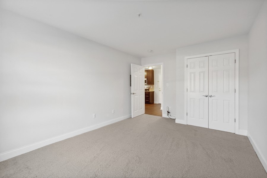 a bedroom with white walls and carpet and a door to a bathroom