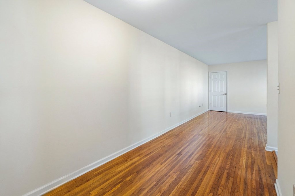 an empty room with white walls and wood floors