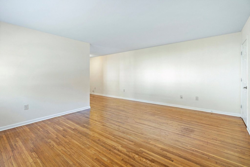 an empty living room with wood floors and white walls