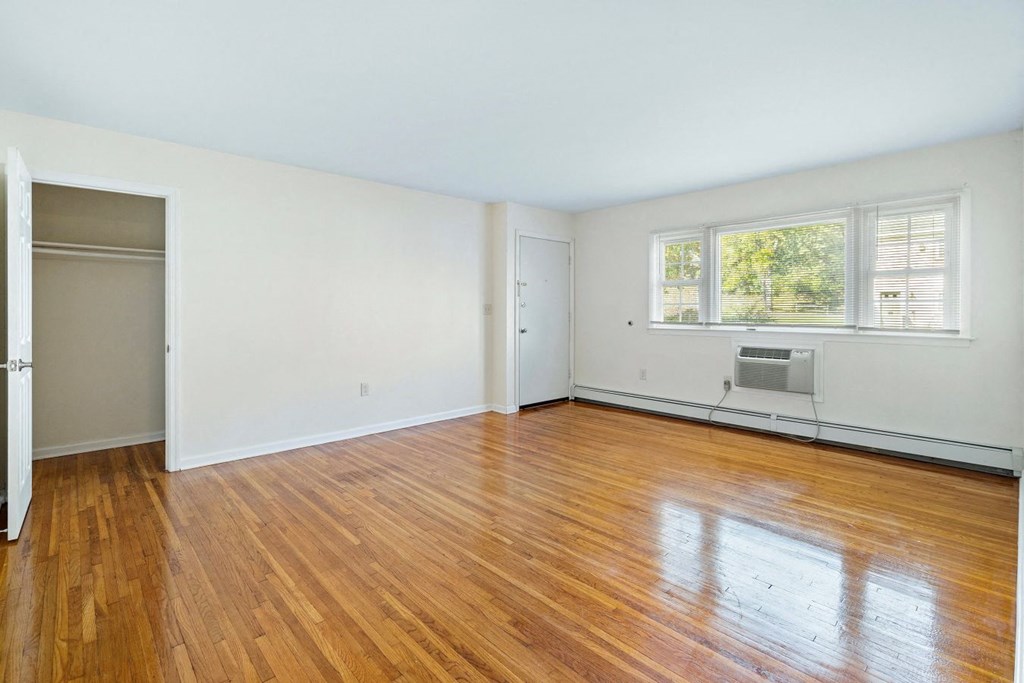 an empty living room with wood floors and a window