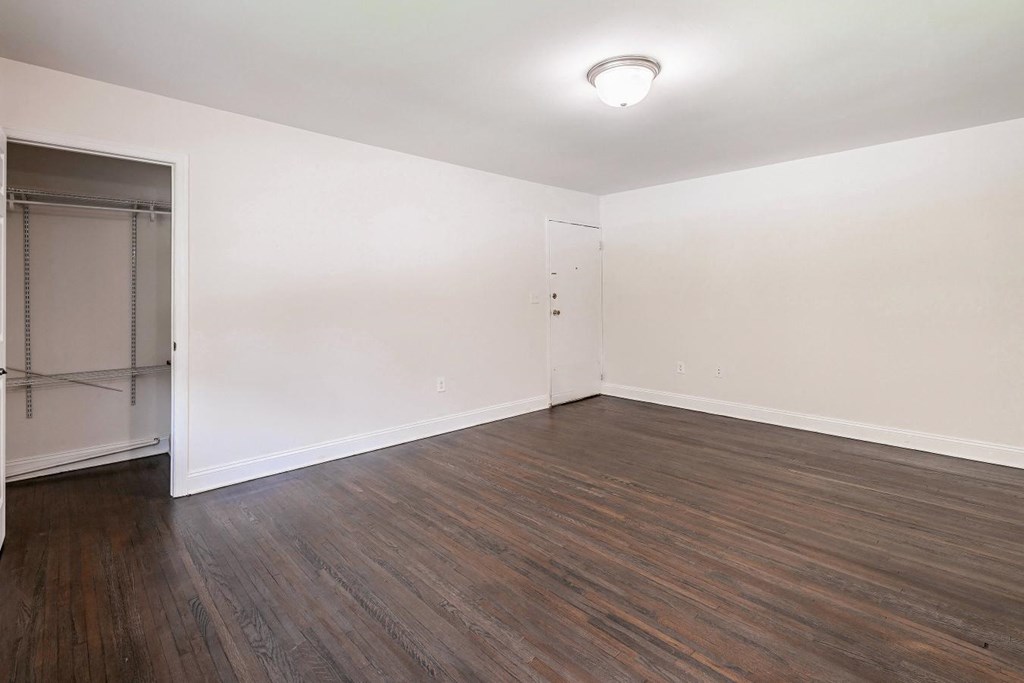 an empty living room with wood flooring and a closet