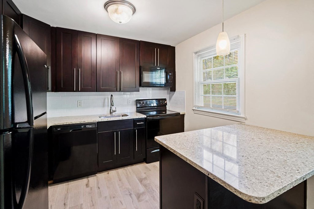 a kitchen with black appliances and a marble counter top