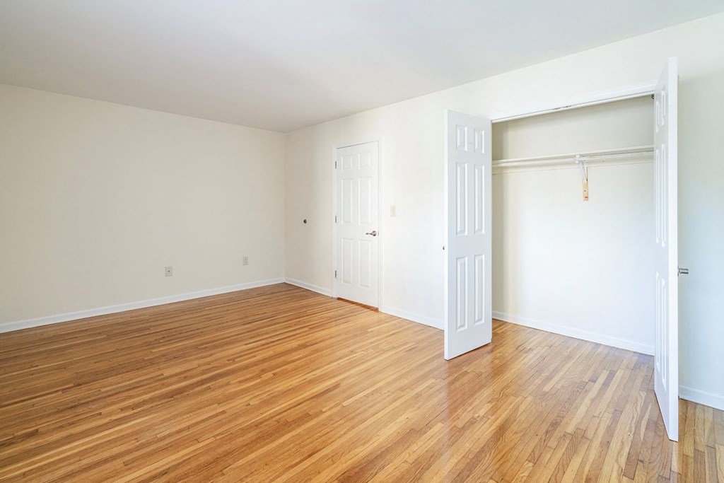 an empty room with wood floors and a white closet