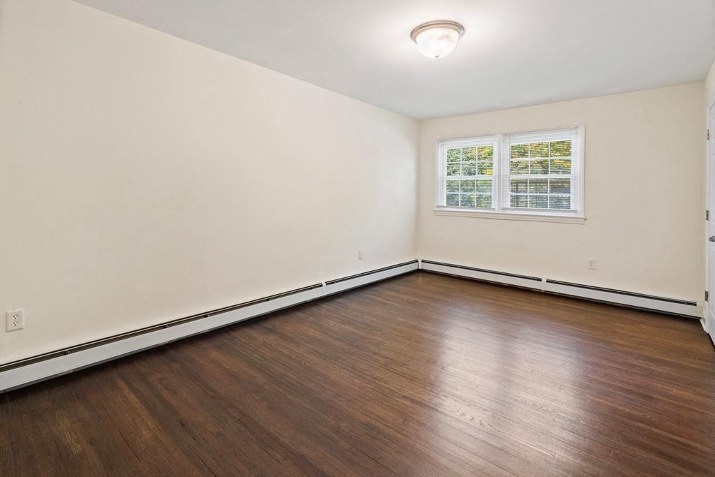 the living room of an empty home with wood floors and a window