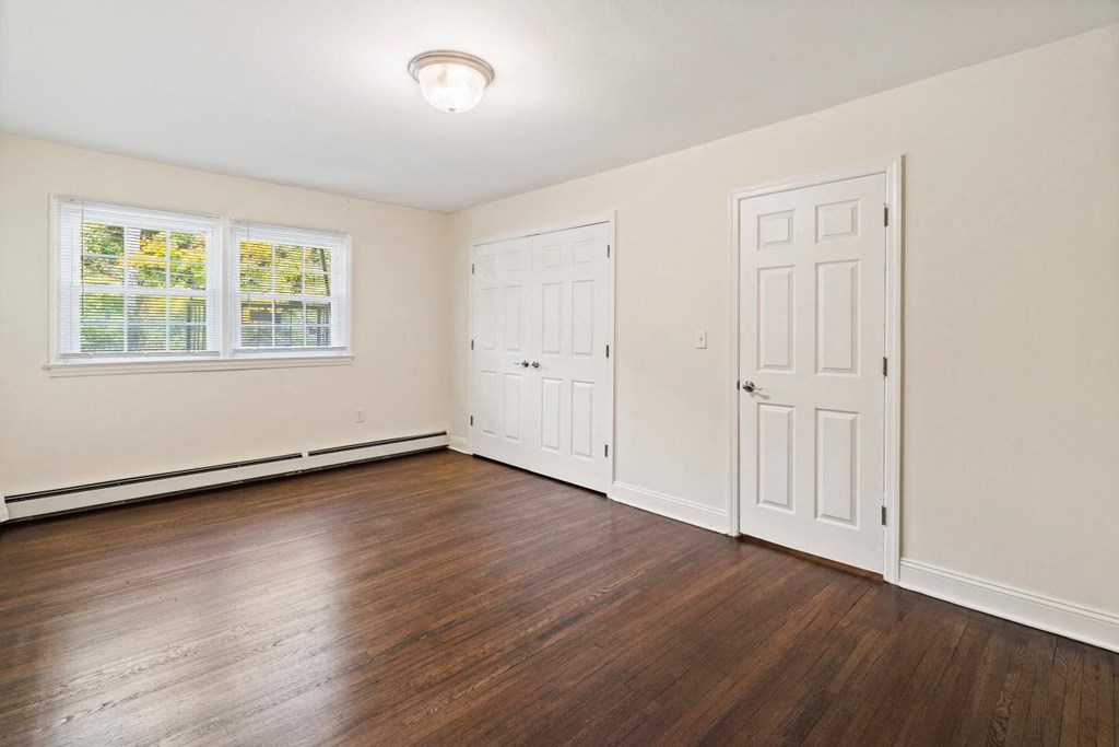 an empty living room with wood floors and white doors