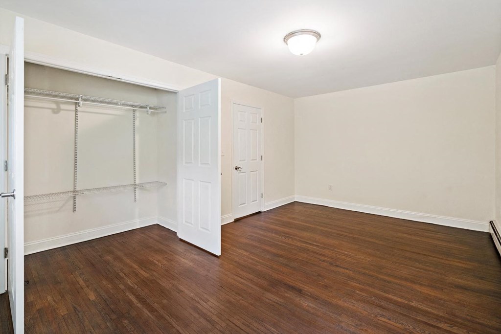 a bedroom with wood flooring and a closet