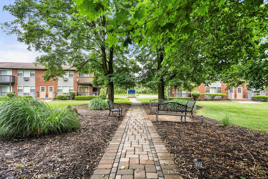 a park with benches and trees in front of an apartment building