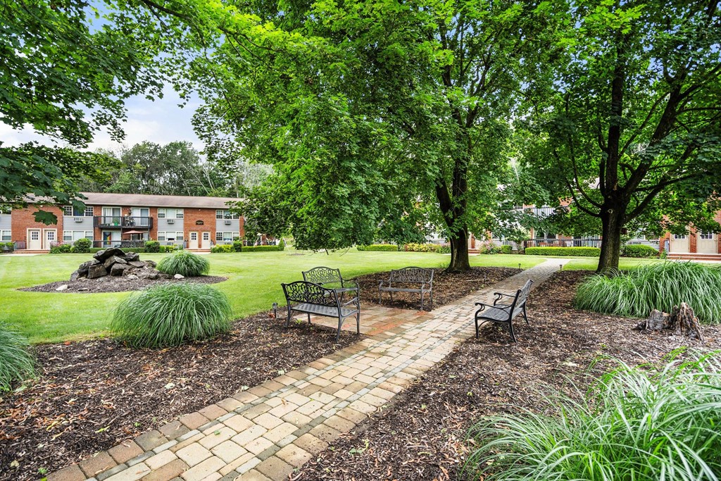 a park with benches and trees in front of a building