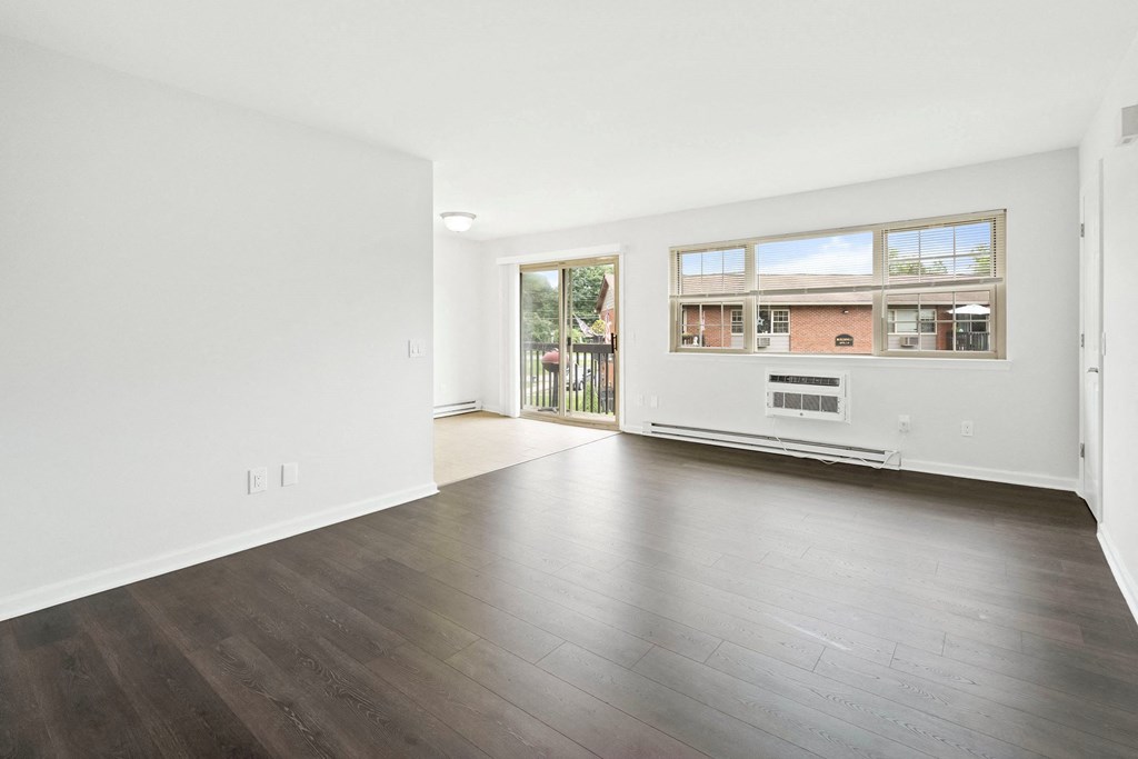 an empty living room with wood floors and a window